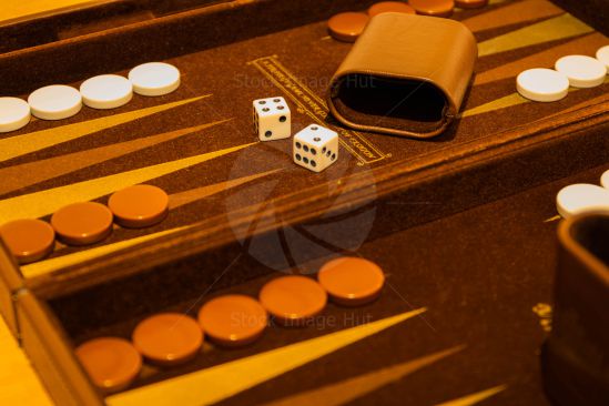 Close up of Backgammon board game with two white dice and game counters