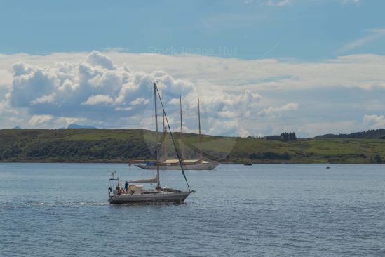 Smaller yacht motors past lager three masted yacht in background. Largs, Scotland image
