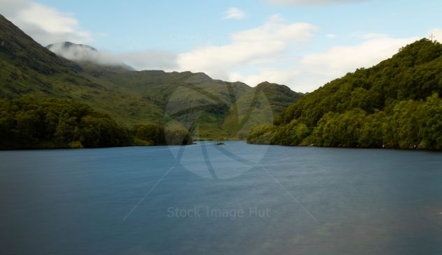 A picturesque, calm loch in the Scottish highlands with a little island sitting in the middle of the loch