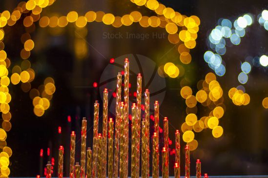 Assortment of Christmas lights, some blurred in the background looking through a rain soaked window