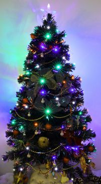 A small brightly coloured, decorated Chrismas tree with fairy lights creating a star burst effect image