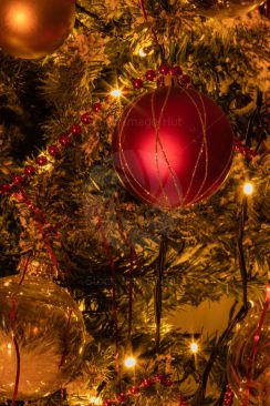 Red bauble on decorated Christmas tree with fairy lights and snow image