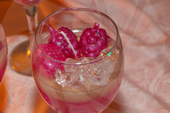 Close up of real wax candle in form of cocktail drink with wax raspberries and wax ice cubes