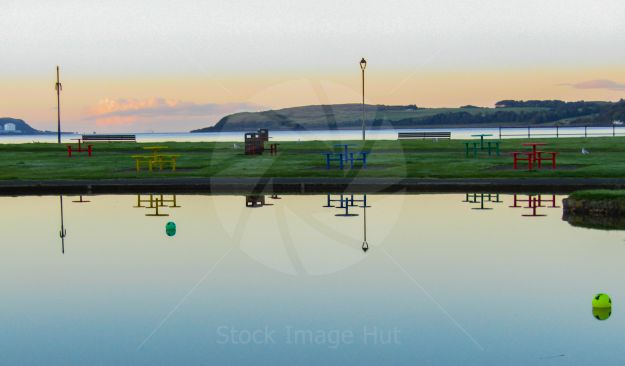 Stunning reflections on a boating pond next to the sea on a very calm morning just after sunrise. This was taken at a little seaside town on the West Coast of scotland.
