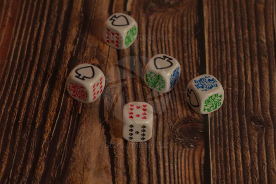 Five poker dice sitting on wooden background