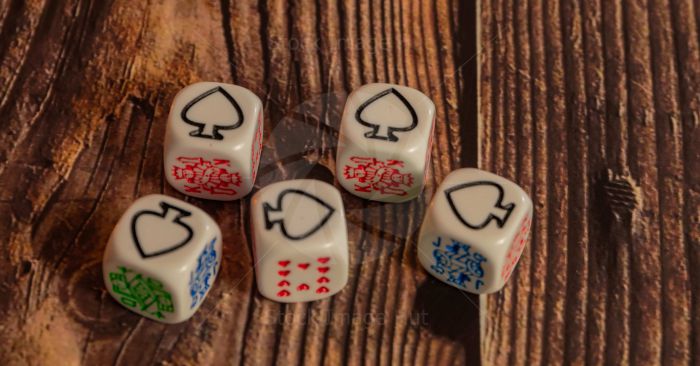 Game of poker dice showing all aces sitting on wooden background