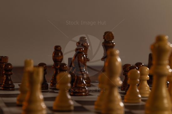 Low down, close up shot of a chess game  with chess pieces closest to camera out of focus