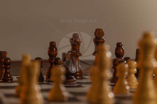 Very low down shot of a wooden chess set focusing on the dark King and Queen