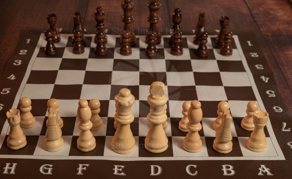 Wooden chess game set up on wooden table ready to play image