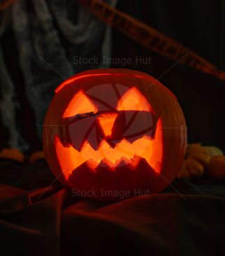 Pumpkin for Halloween with scary face carved out and lit by candle inside image