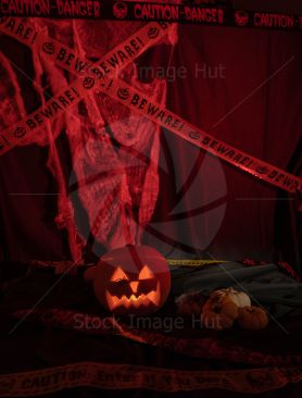 Image of a pumpkin at halloween with scary face carved and lit up by candle inside with scary backdrop