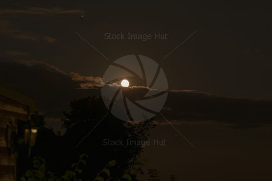 Bright moon rising above clouds on a summer night