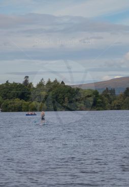 Paddle boarder and canoe enjoying loch Lomond on a beautiful summer day image