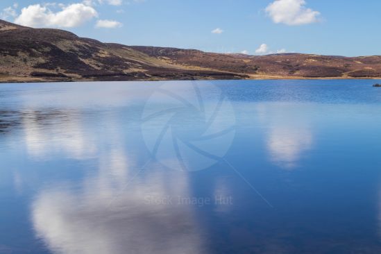 Clouds reflecting on calm loch in winter sunshine