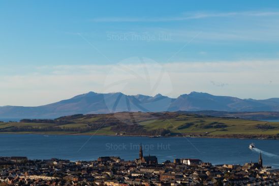 Picturesque seaside town with ferry crossing to Millport and distant mountains of Arran in background,  West Coast of Scotland