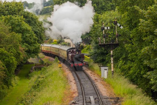 Steam train coming into station puffing huge amounts of steam from engine image