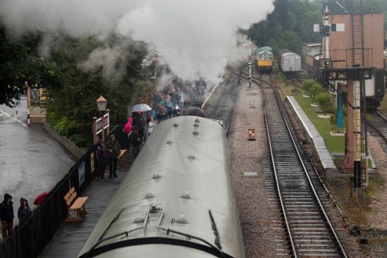 Passengers waiting to board steam train in pouring rain