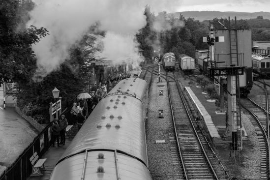 Steam train arriving at station on a very rainy day image