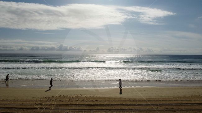 Joggers on beach as sun begins to go down on surfers paradise, Australia