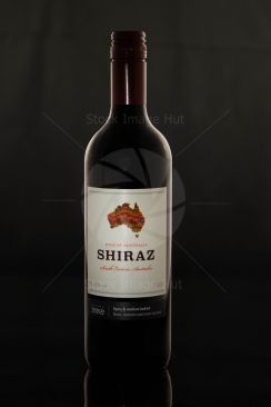 A bottle of red wine with dark background and rim lights